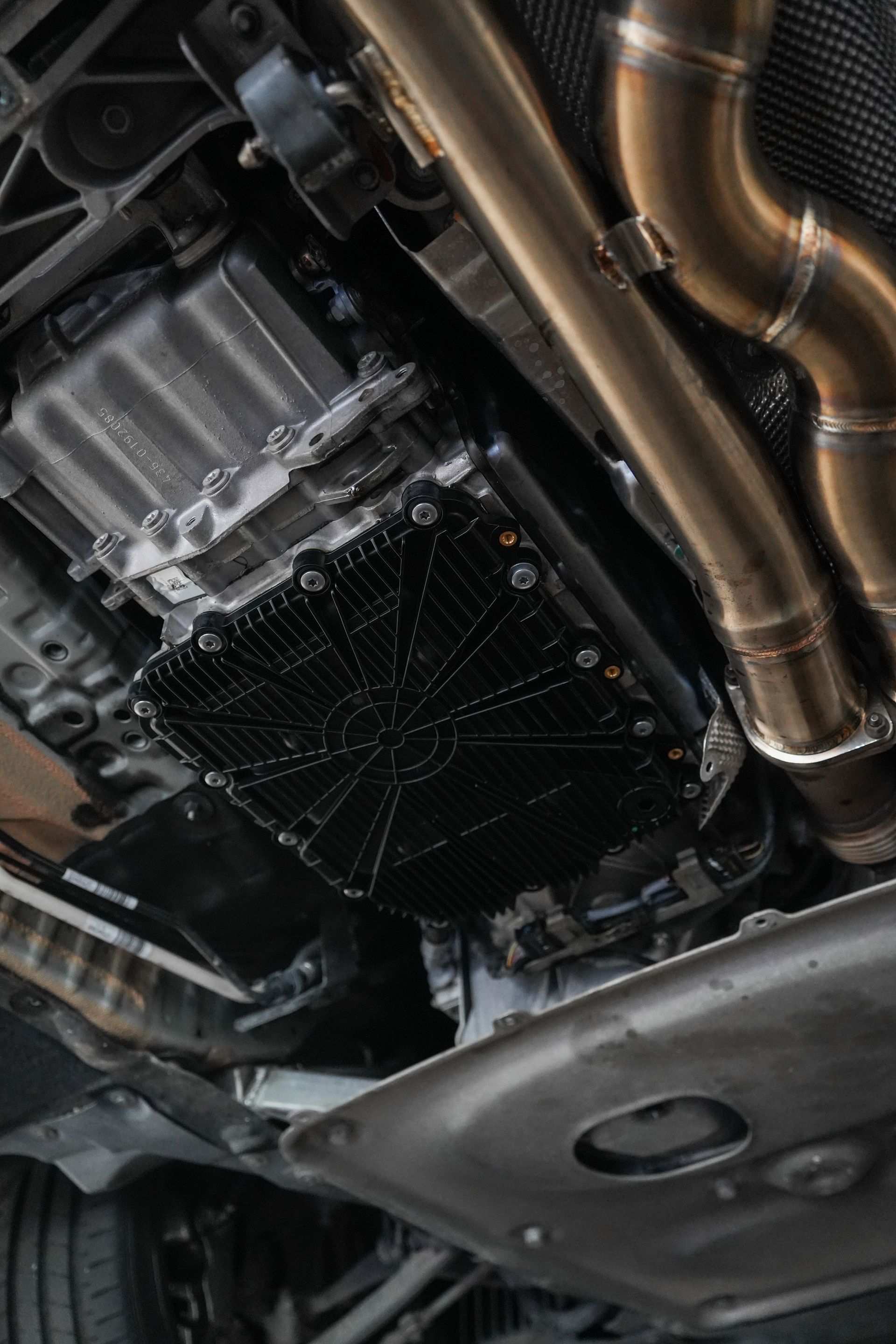 Undercarriage of a car showing metal exhaust pipes and black engine components