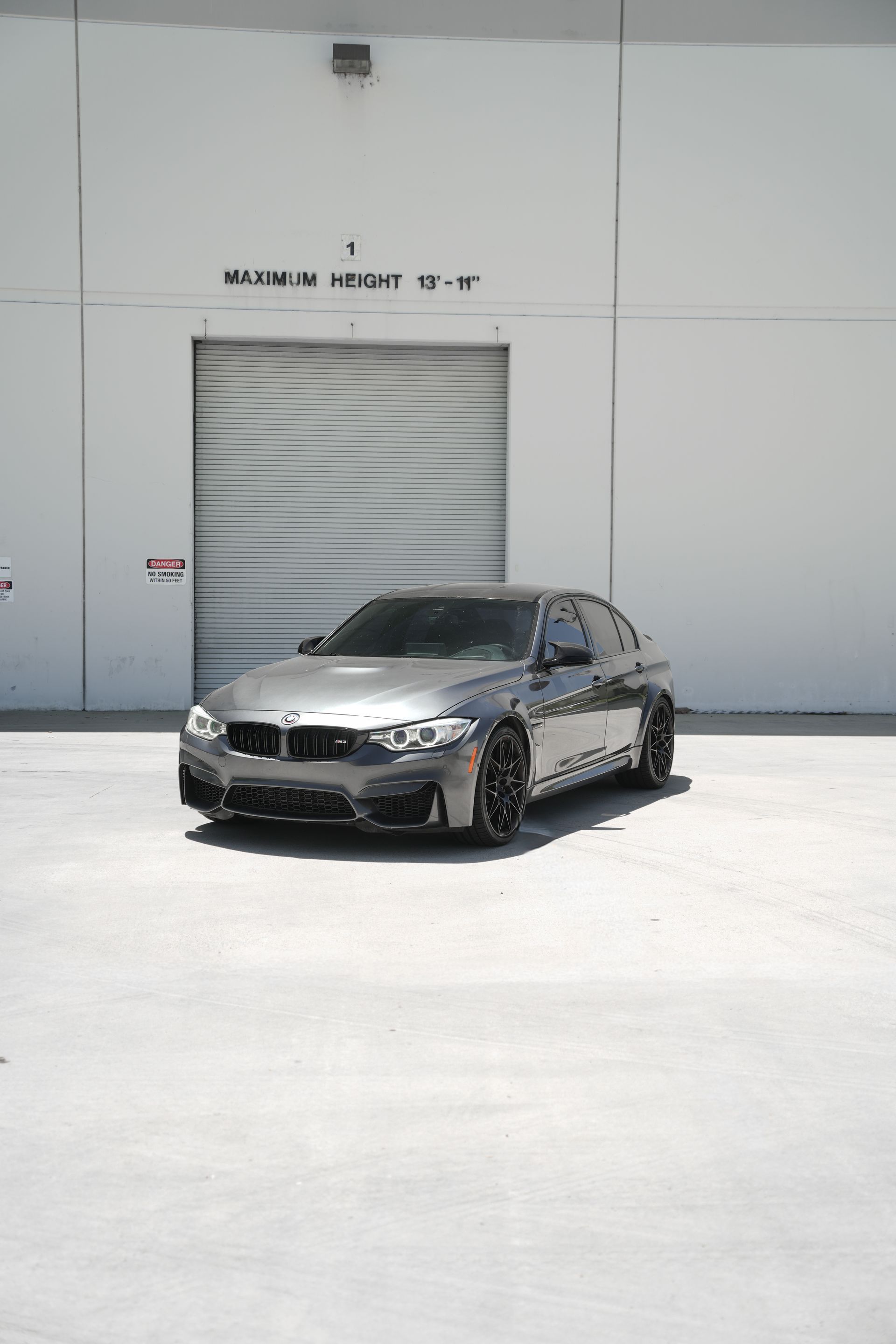 Silver sedan parked in front of a white industrial warehouse with a closed roll-up door.