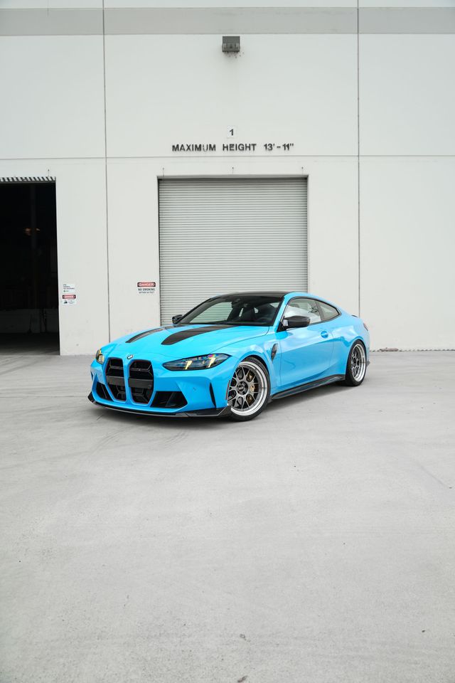 Bright blue sports car parked in front of a white industrial building.