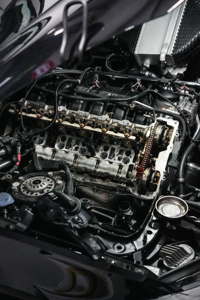 Car engine with exposed components, showing oily, damaged parts under the hood