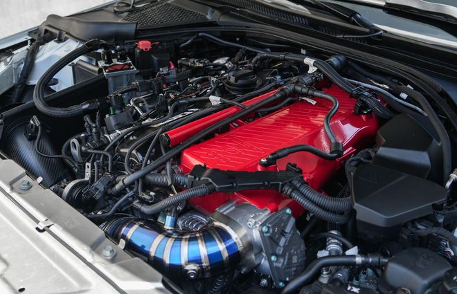 Close-up of a car engine bay with a red engine cover and blue-and-black intake pipe