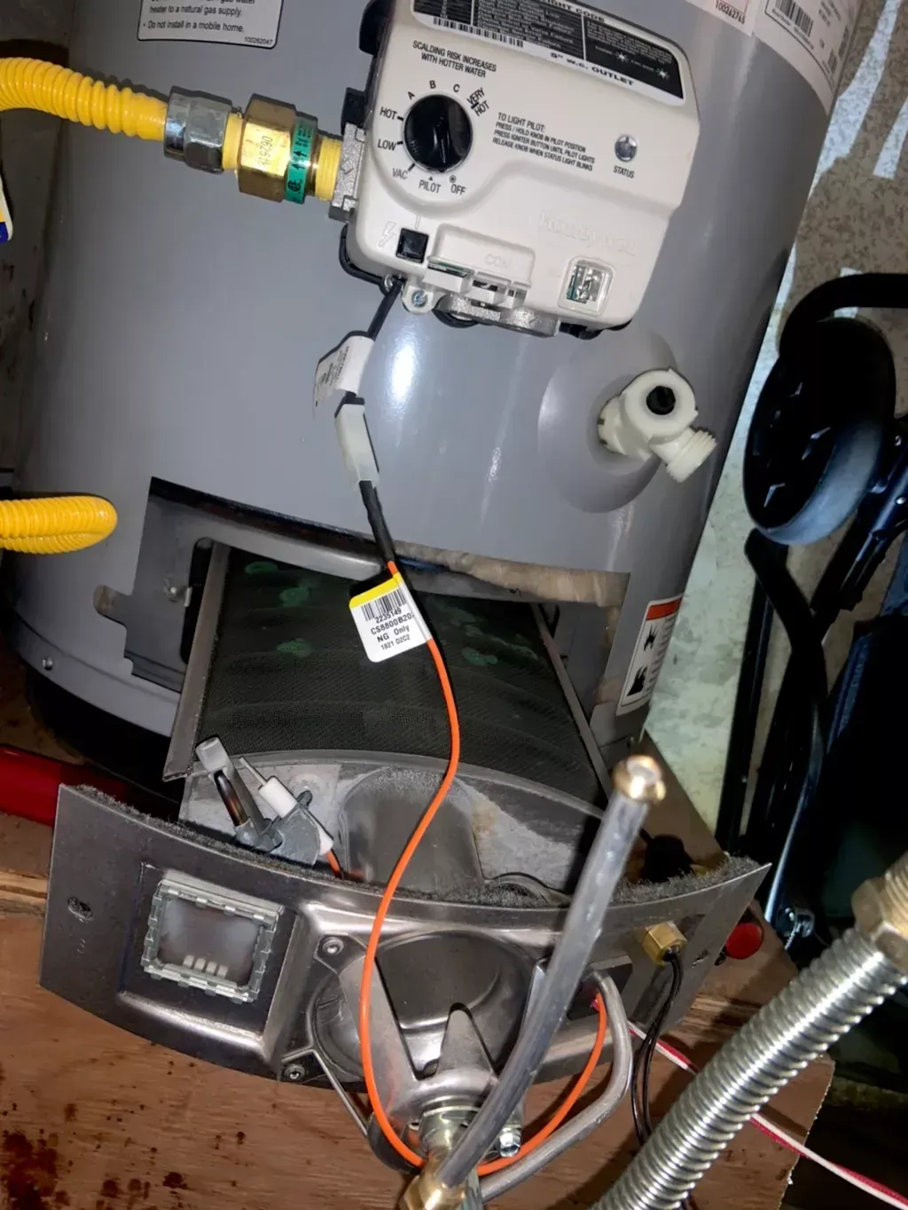 Water heater with open access panel, showing burner assembly and gas lines.