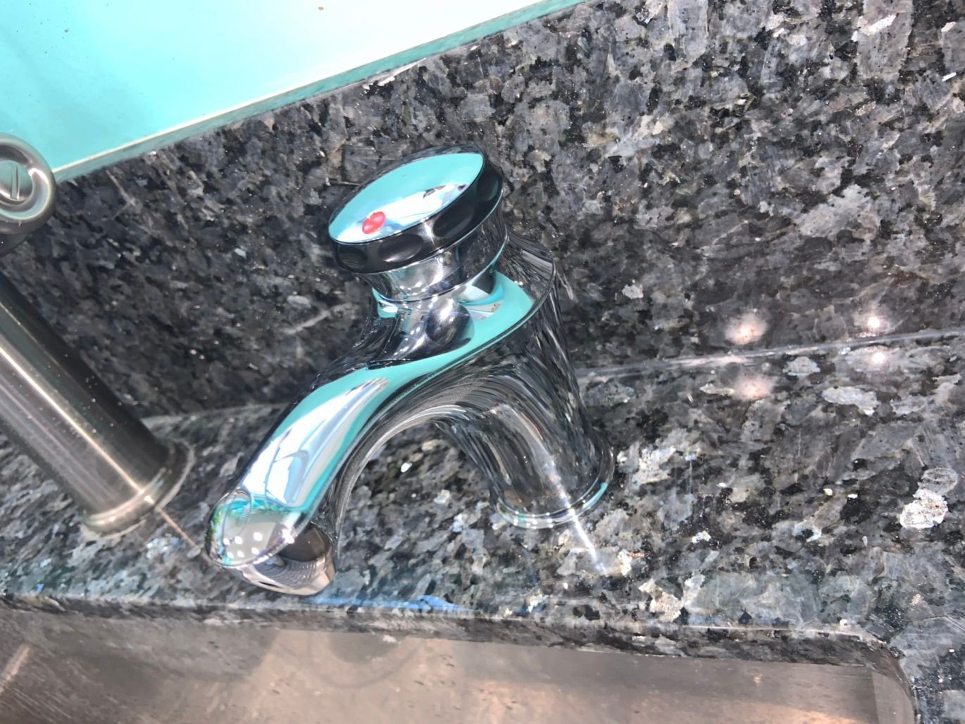 Chrome faucet on a granite countertop, turquoise details.