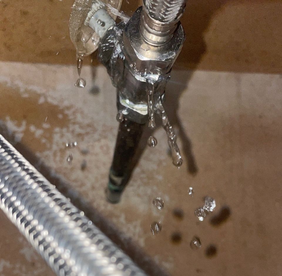 Two service workers repairing concrete on a sidewalk next to a company truck.
