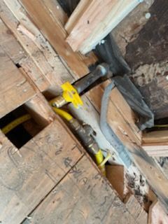 Gas pipes with yellow shutoff valves in a wooden structure.