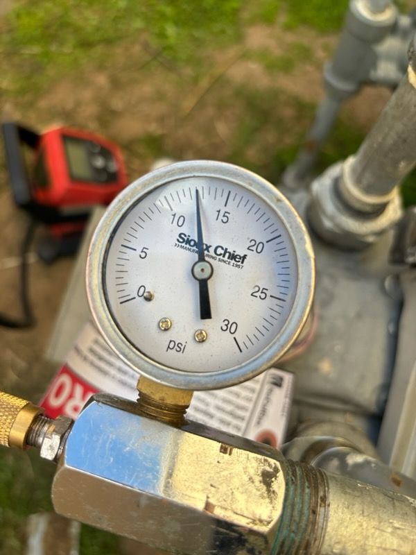 Pressure gauge with a needle reading approximately 11 psi, attached to a metal pipe.