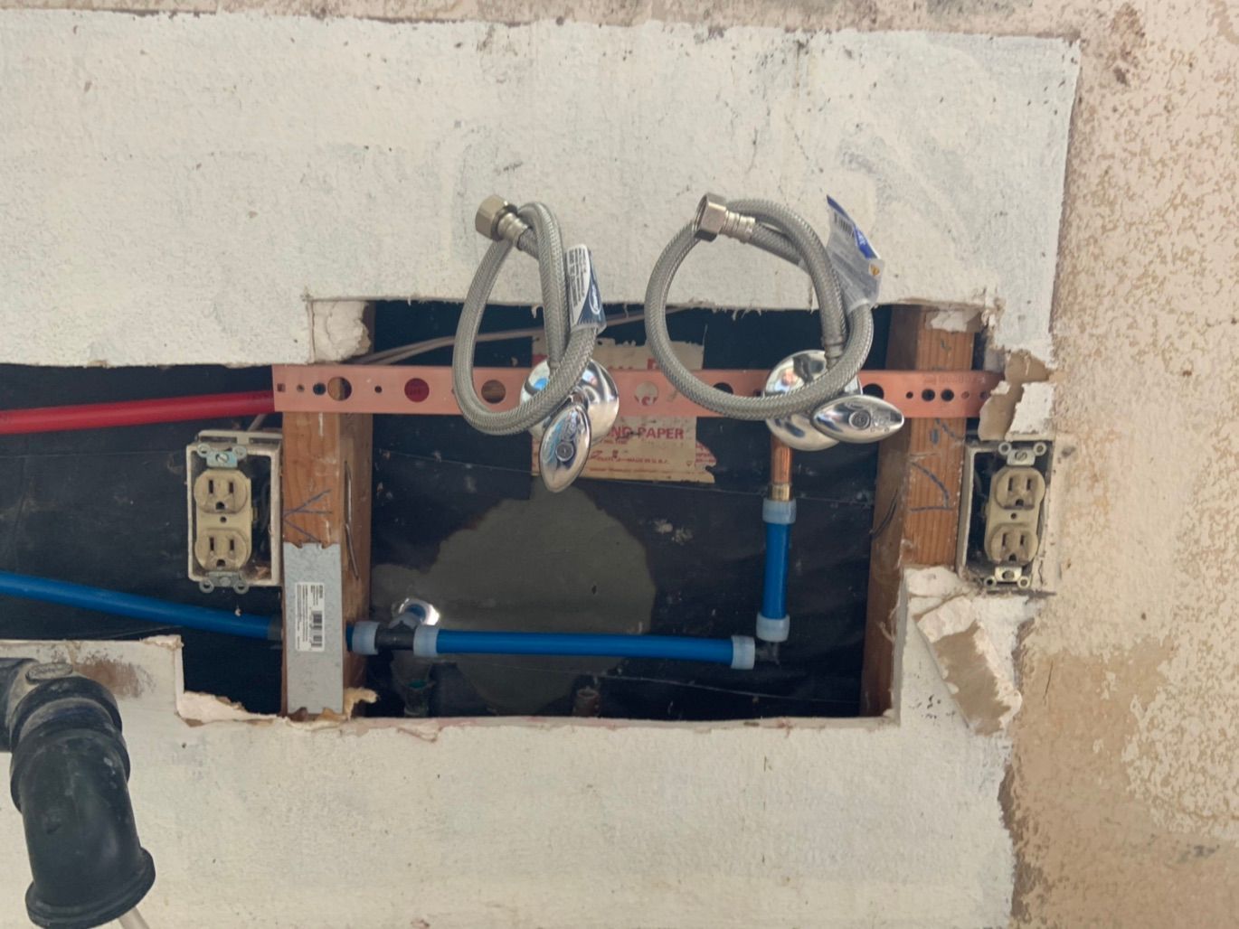 Water pipes and electrical outlets inside a wall.