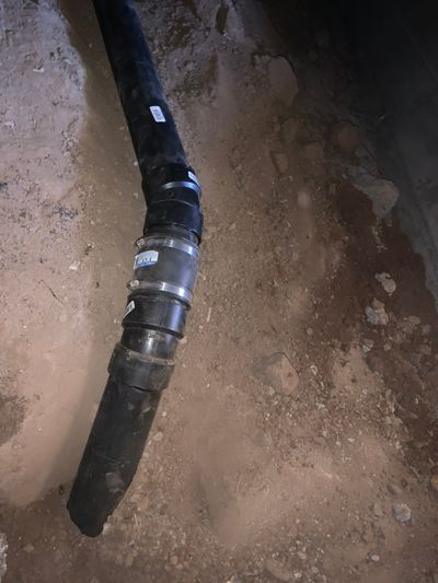 Black plumbing pipes in a dirt trench, connected with couplings.