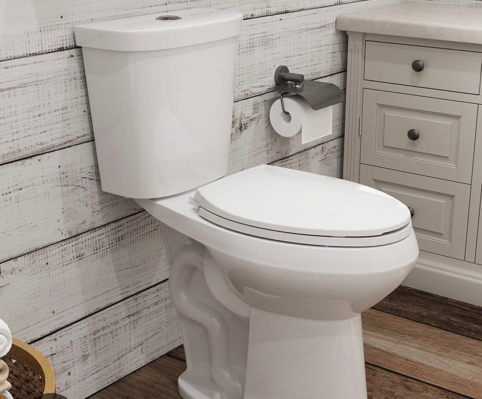 White toilet in a bathroom with wood-paneled walls, a cabinet, and a toilet paper holder.