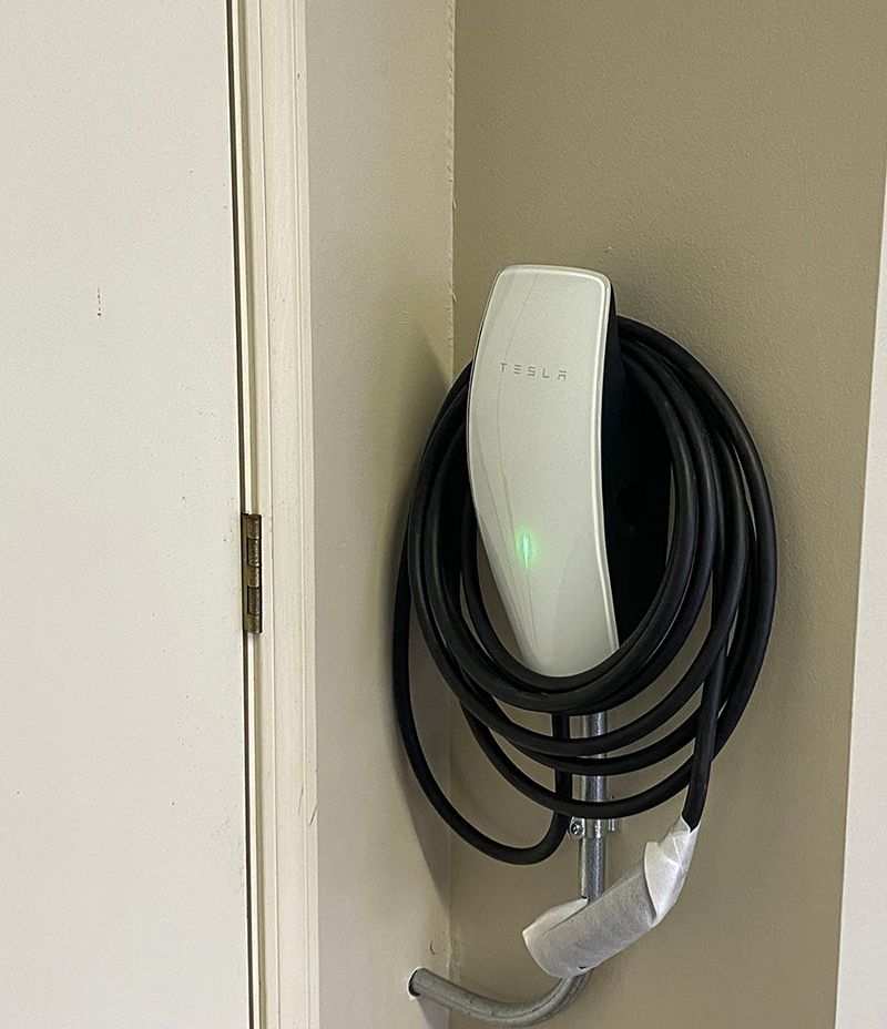 A tesla charging station is hanging on a wall next to a door