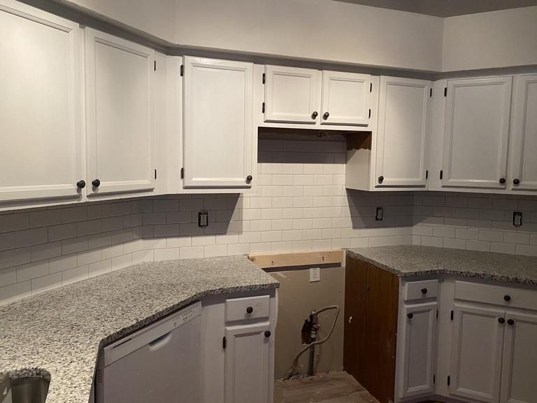 a kitchen with white cabinets and granite counter tops .
