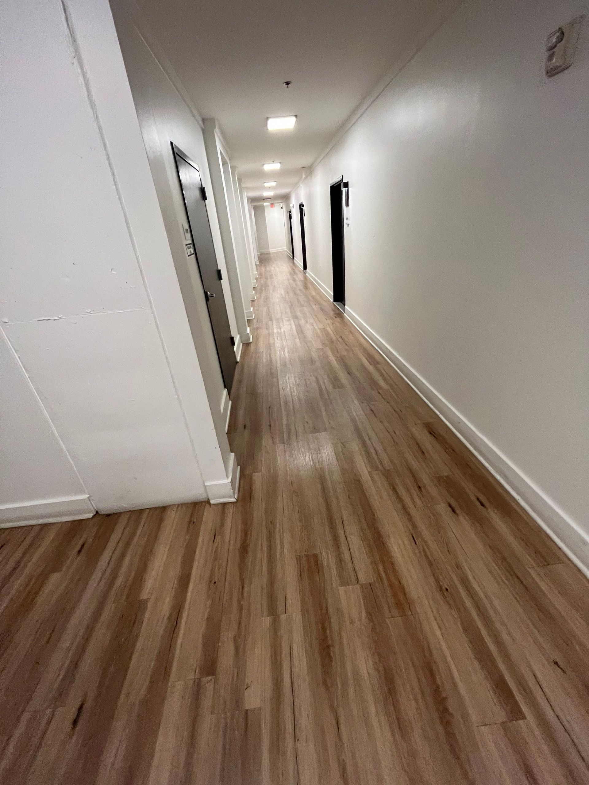 a long hallway with wooden floors and white walls .