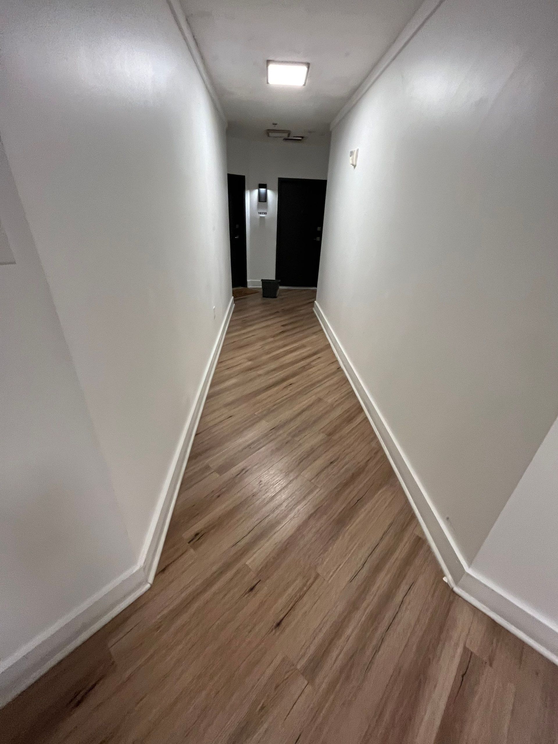 a long hallway with wooden floors and white walls .