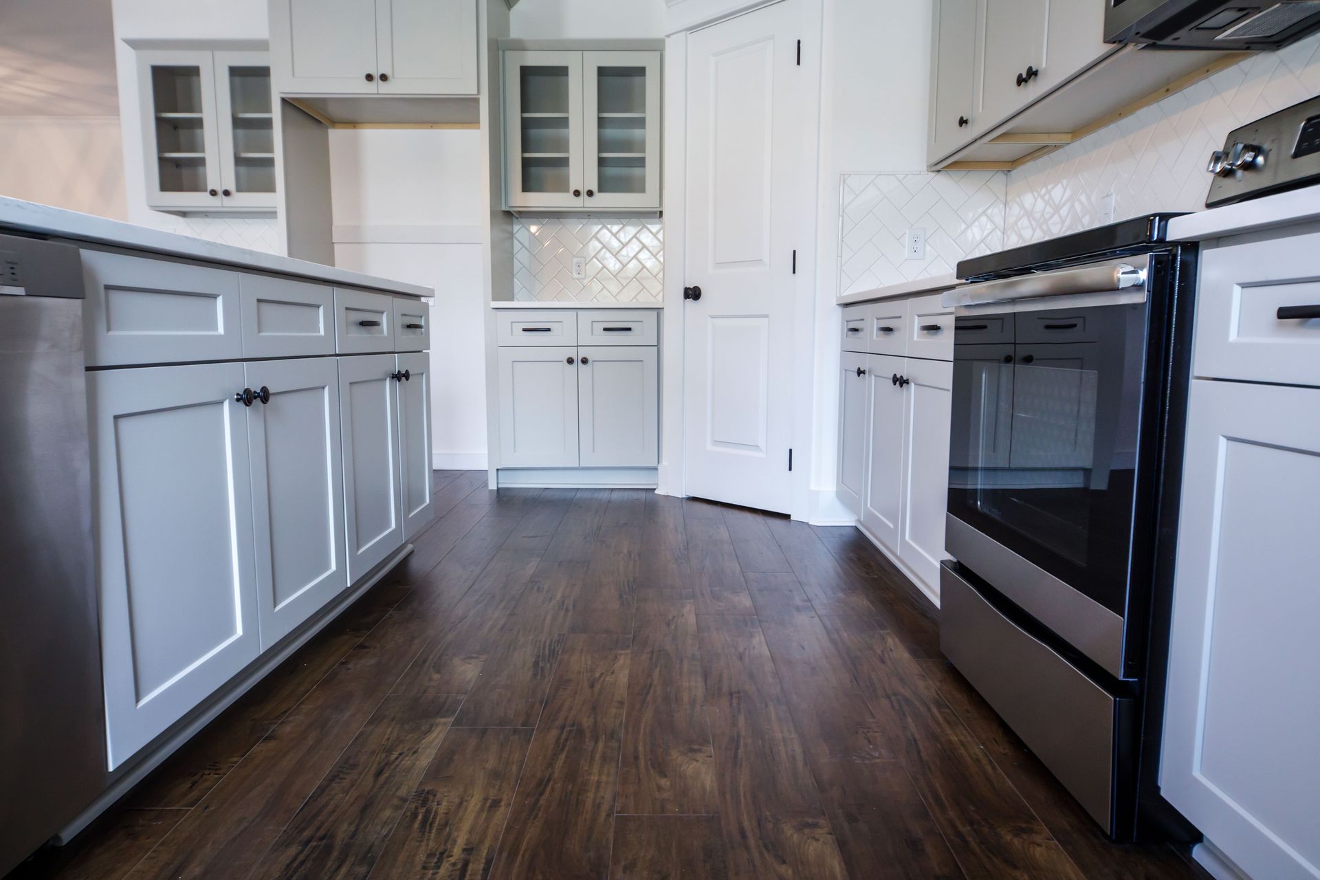 Kitchen with white cabinets, stainless steel appliances, and dark wood floors.