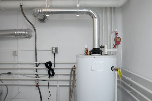 Two outdoor HVAC units on gravel beside a wooden wall
