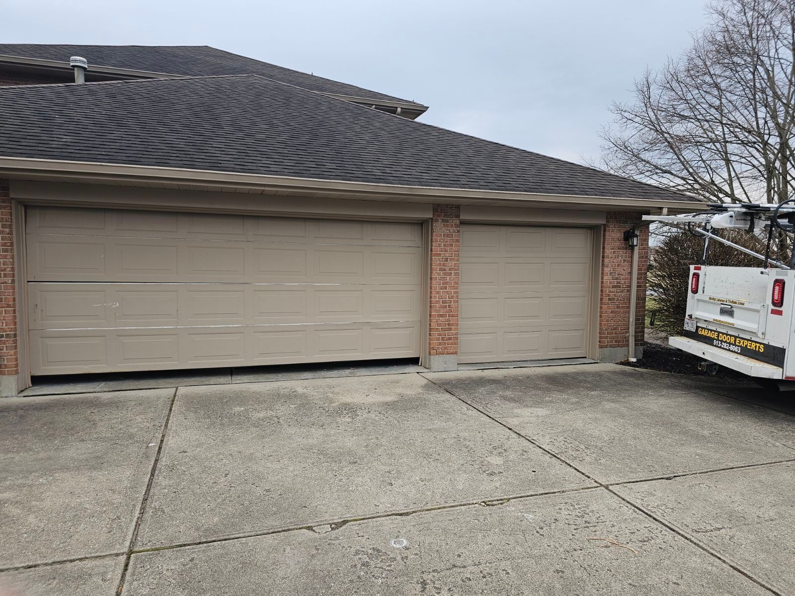 Suburban driveway with two garage doors and a white utility van parked on the right.