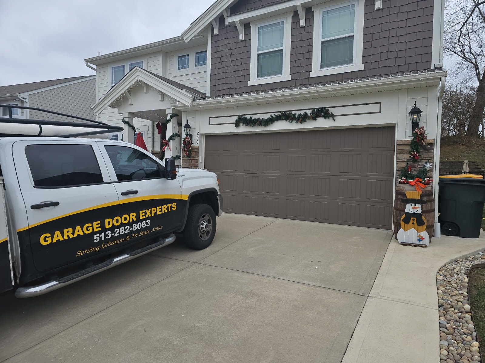 Suburban house with closed brown garage door; service van parked in driveway.