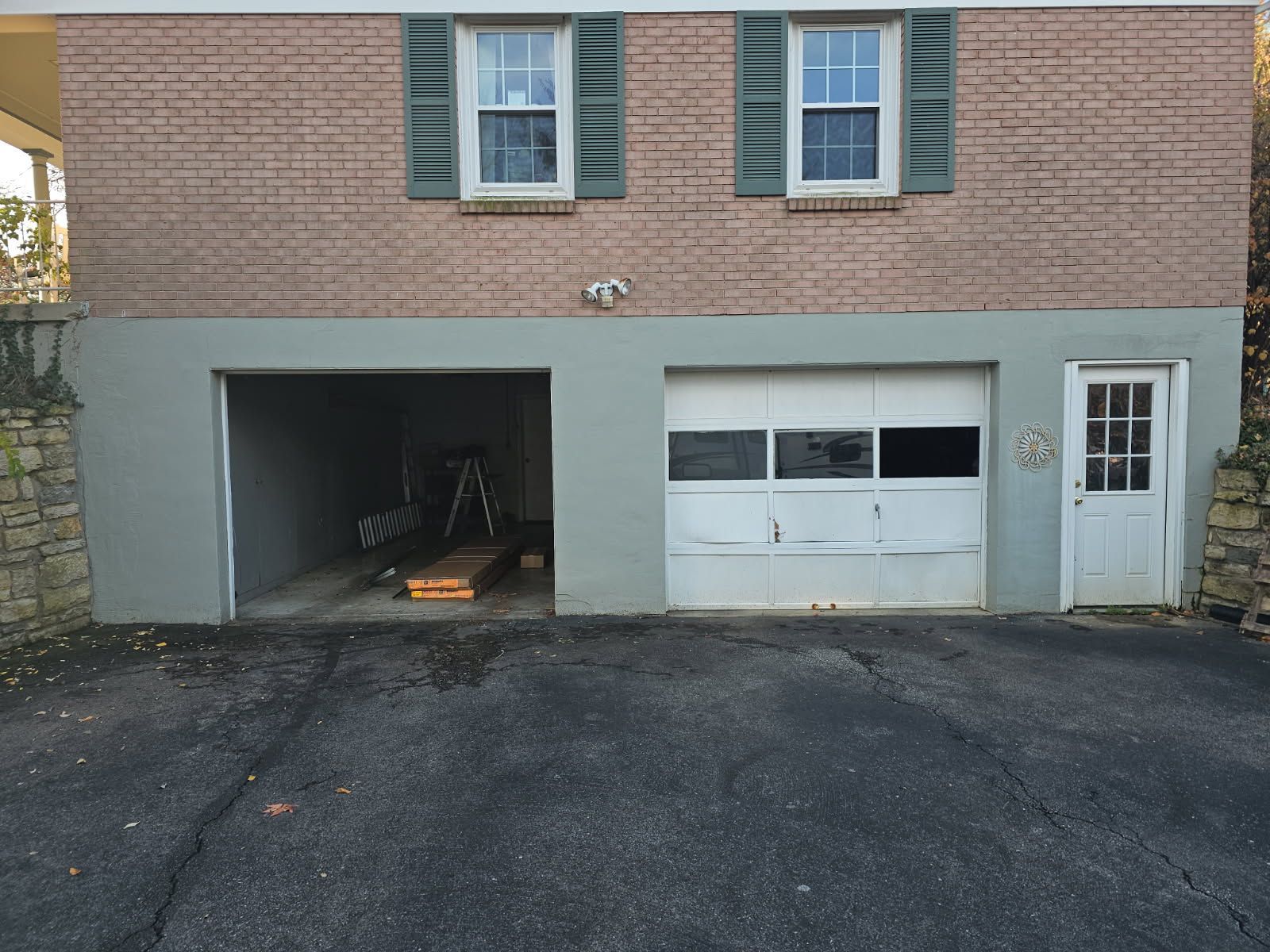 Brick townhouse garage with a left open bay and a white garage door beside a side entry door