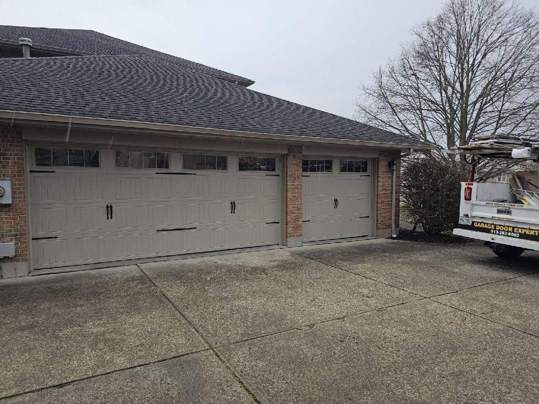 Suburban house with two garage doors, gravel driveway, and a utility truck parked at right.