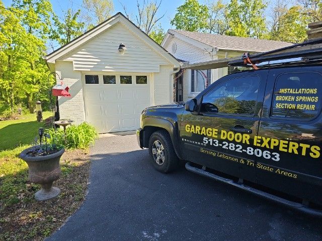Garage Door Experts truck parked beside a white garage in a suburban driveway.