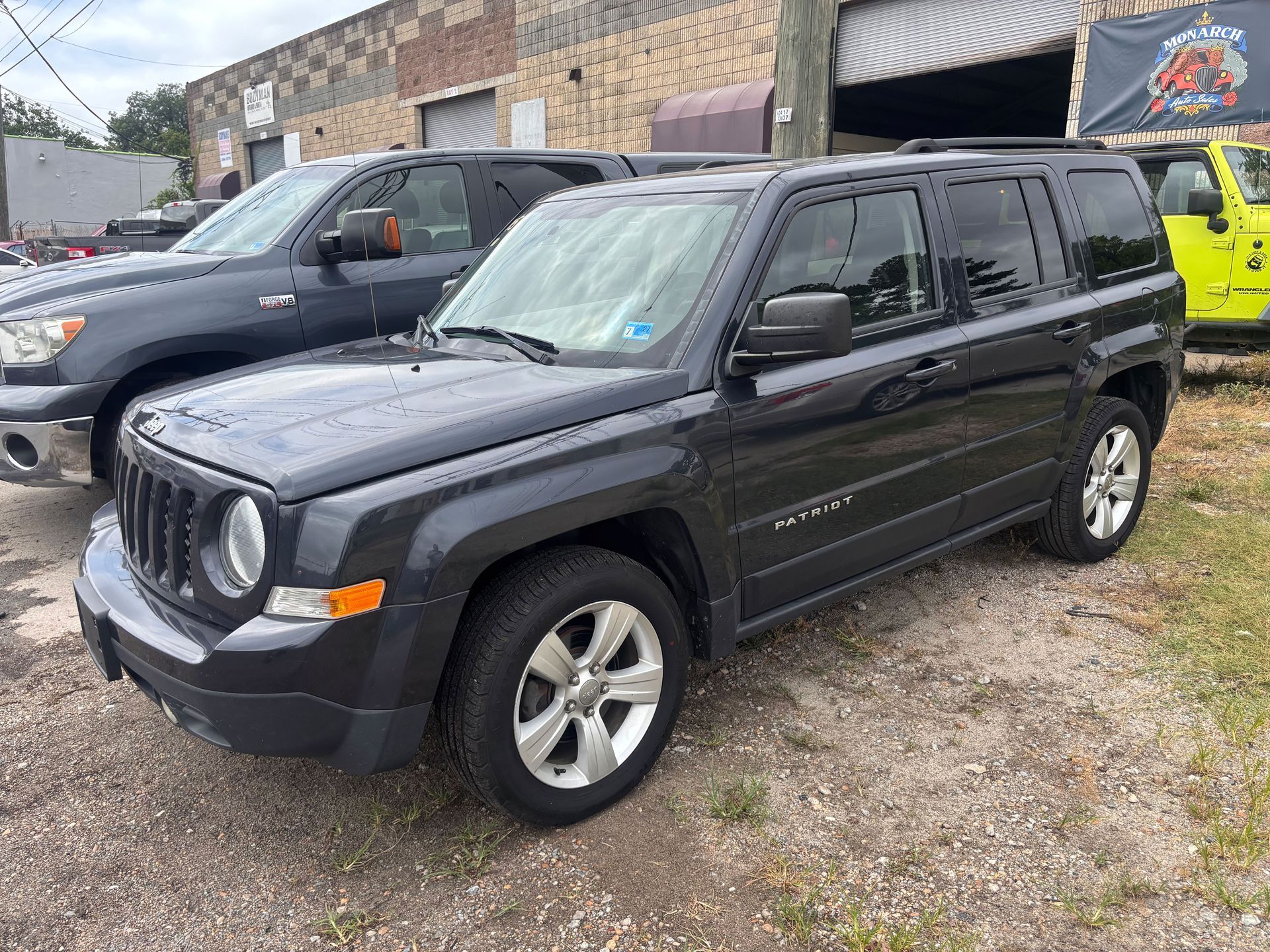 Black SUV parked outside a stone building beside other vehicles.