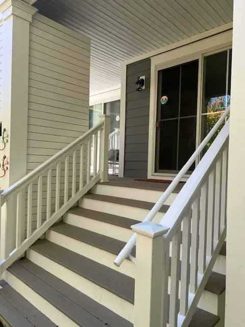 Front porch stairs with white railings leading to a dark front door under a covered entry.