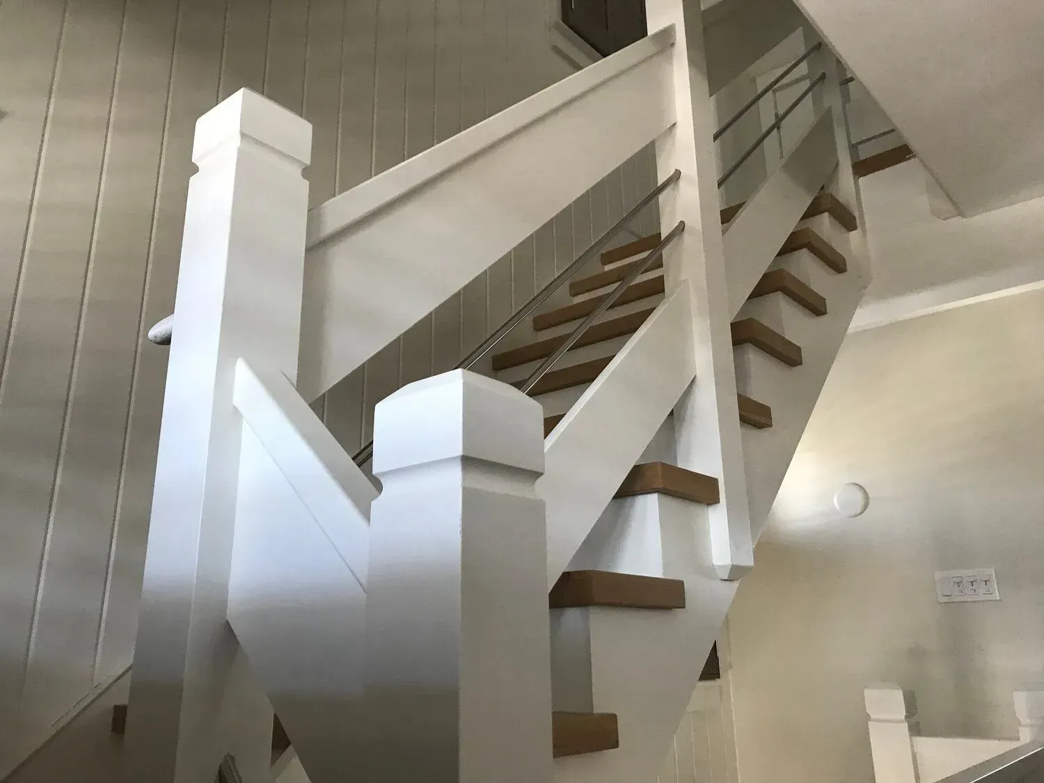 Indoor white staircase with wooden steps and railings in a bright hallway