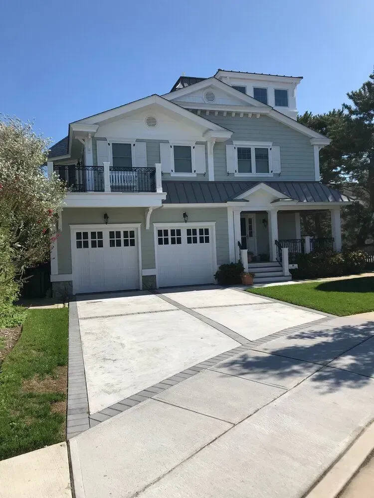 Two-story gray house with a double garage and a wide driveway on a sunny day