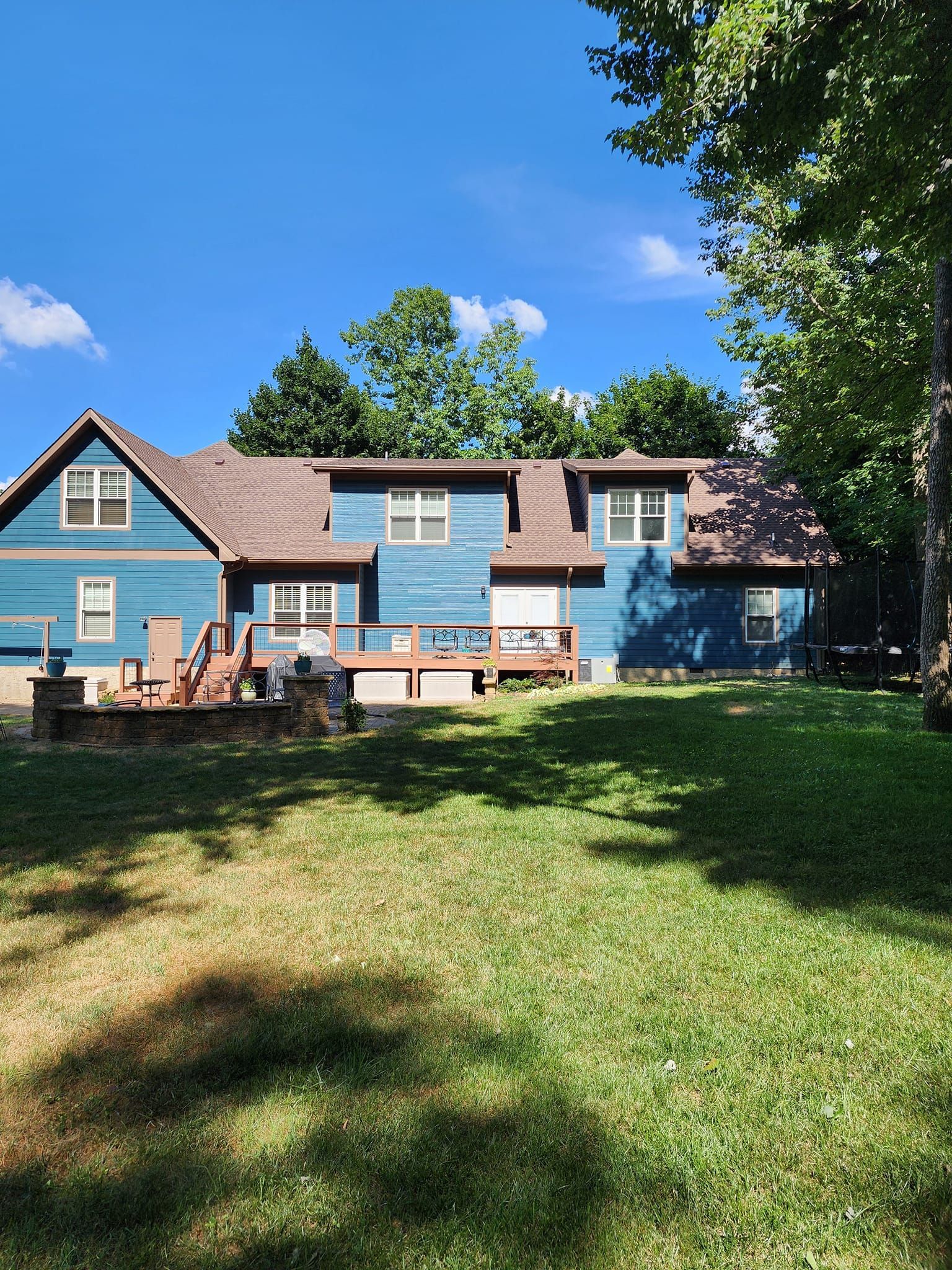 A blue house with a brown roof is sitting in the middle of a lush green field.