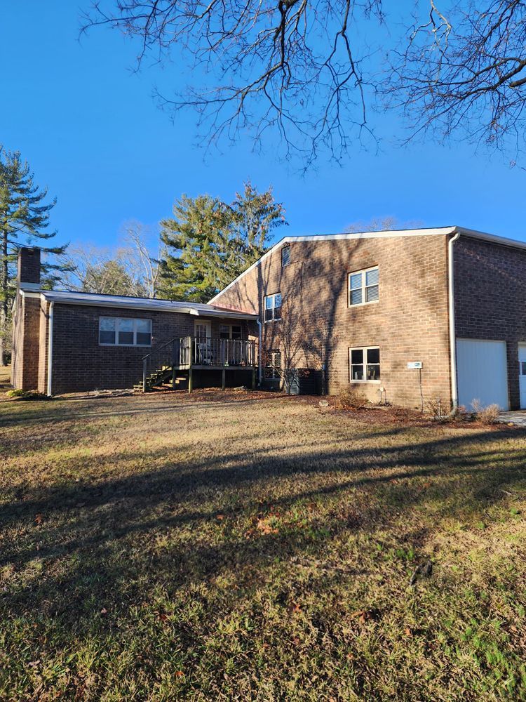A large brick house is sitting on top of a grassy hill.