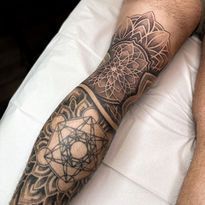 Leg tattoo featuring geometric mandala and Metatron's Cube designs in black ink.