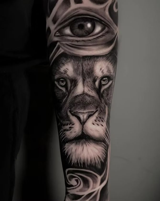 Black and white tattoo of a lion's face with a watchful eye above.