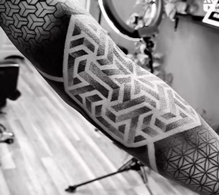 Black and white geometric tattoo on an arm, with various patterns and designs.