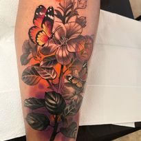 Tattoo of a butterfly and flowers with a vibrant orange and purple background.