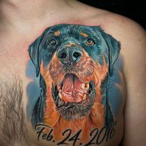 Color tattoo of a Rottweiler dog's face, with mouth open, smiling.