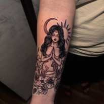 Tattoo of a woman with earth for a belly, hands clasped in prayer, moon, sun, and flowers.