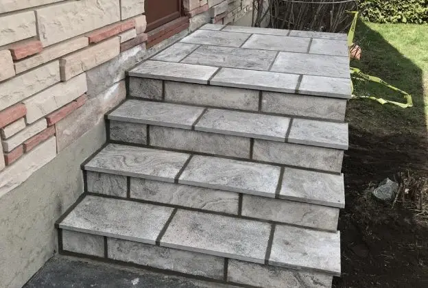 Stone steps beside a brick wall leading up to a yard area