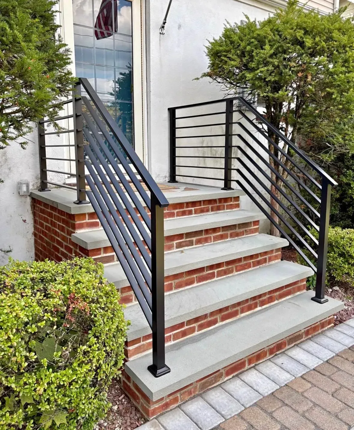 Front steps with black metal railings leading to a brick-and-concrete entrance.