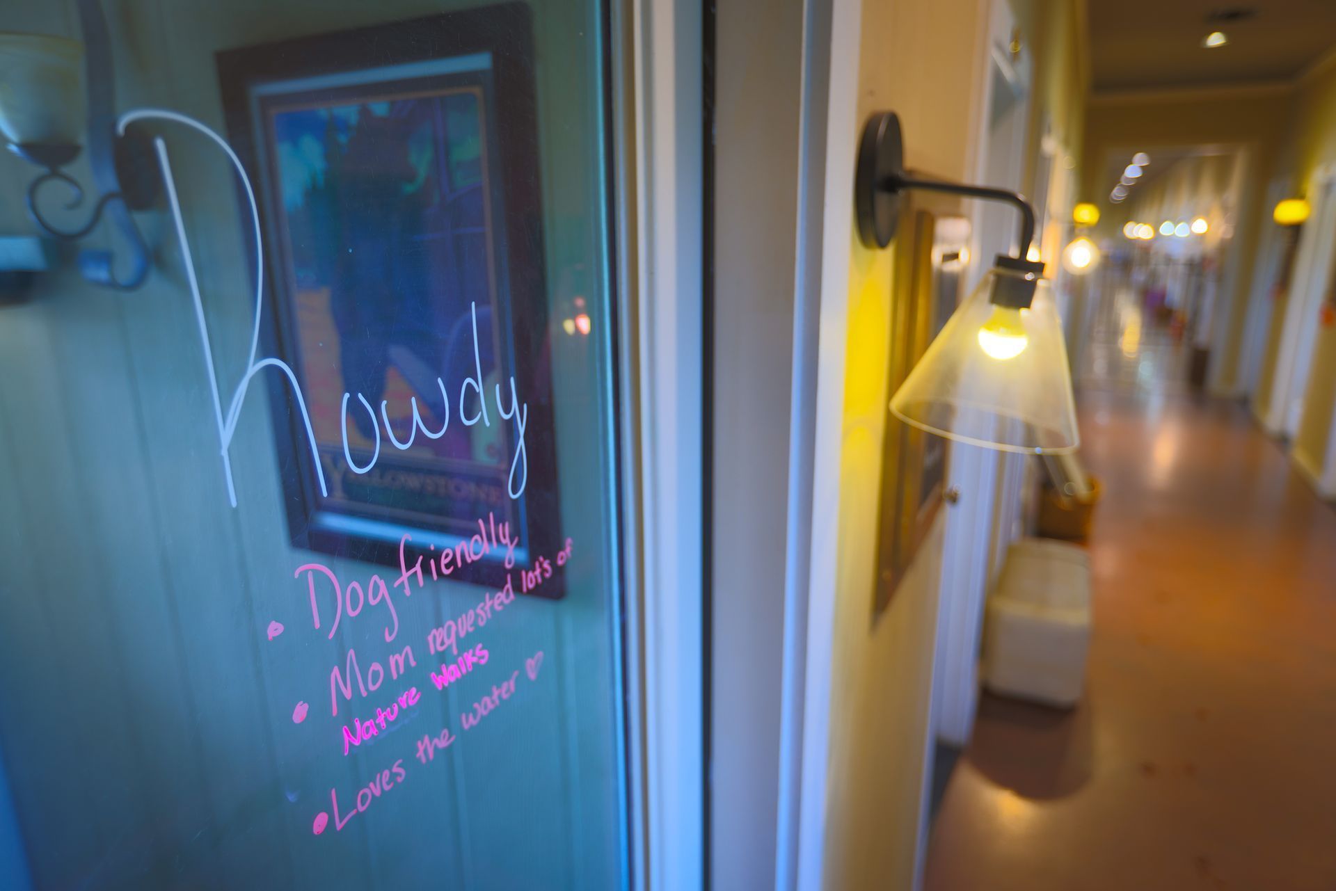 Cozy hallway with a glass door covered in pink handwritten notes and a lit wall lamp