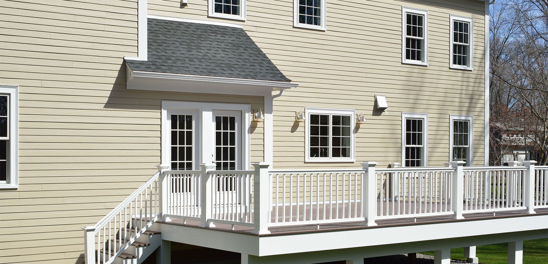 House exterior with deck and stairs. Beige siding, white trim and railings.