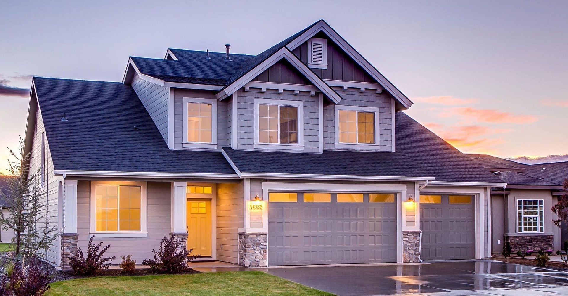 Two-story gray house with a dark roof and a two-car garage at dusk.