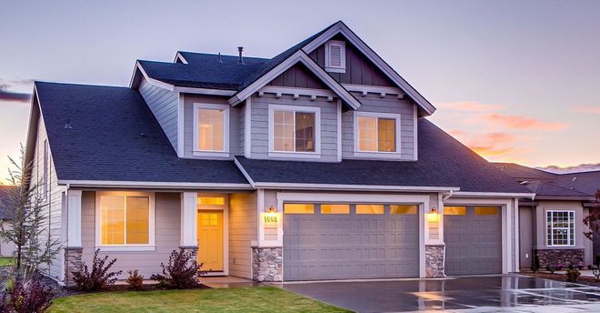 Two-story gray house with a dark roof and a two-car garage at dusk.