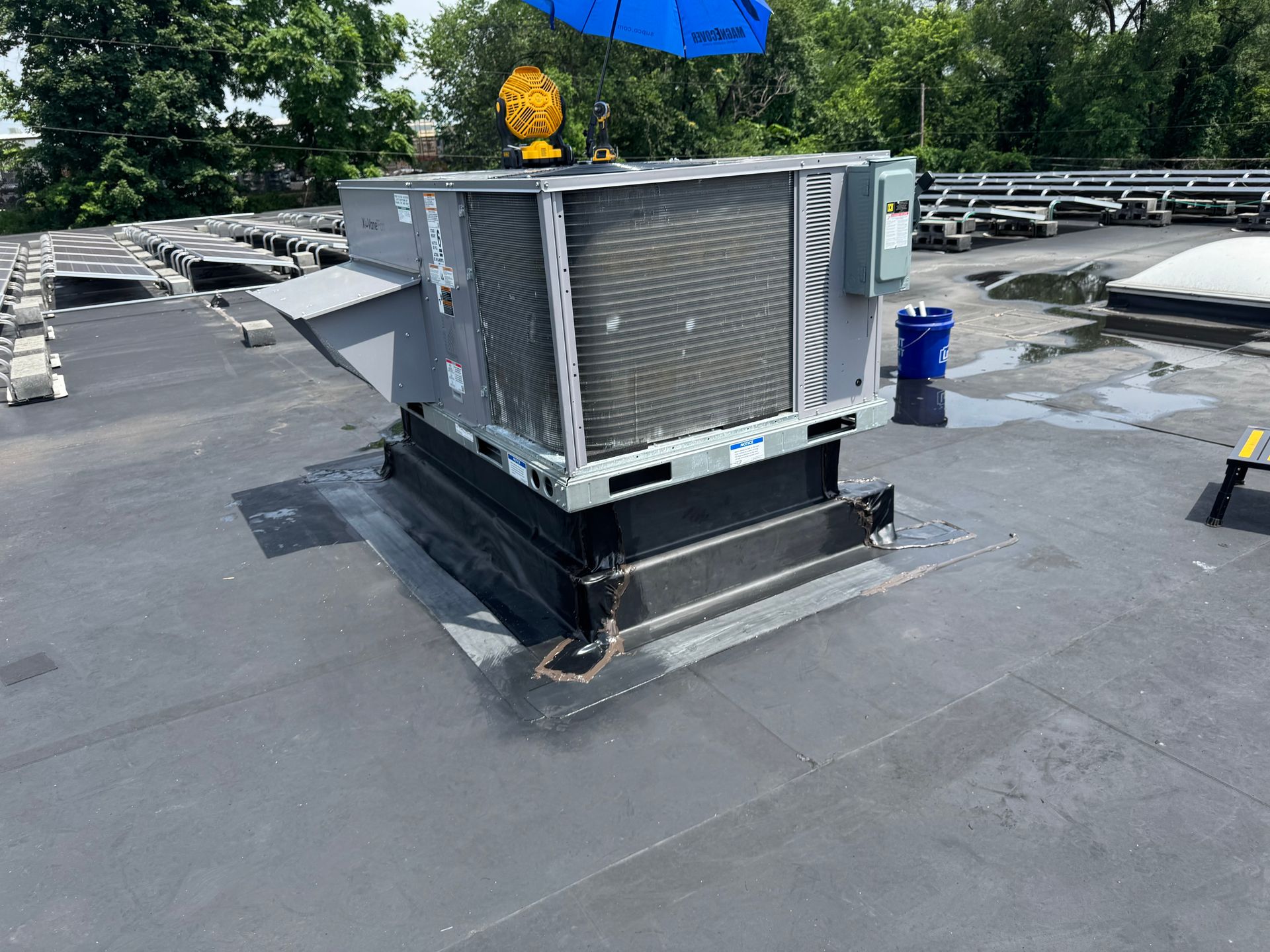 HVAC unit on a flat roof. Blue bucket and sunny sky.