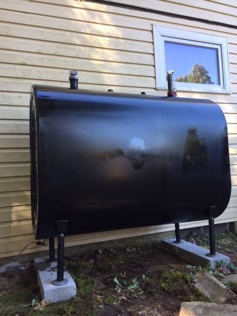 Black oil tank outside a building, on concrete blocks.
