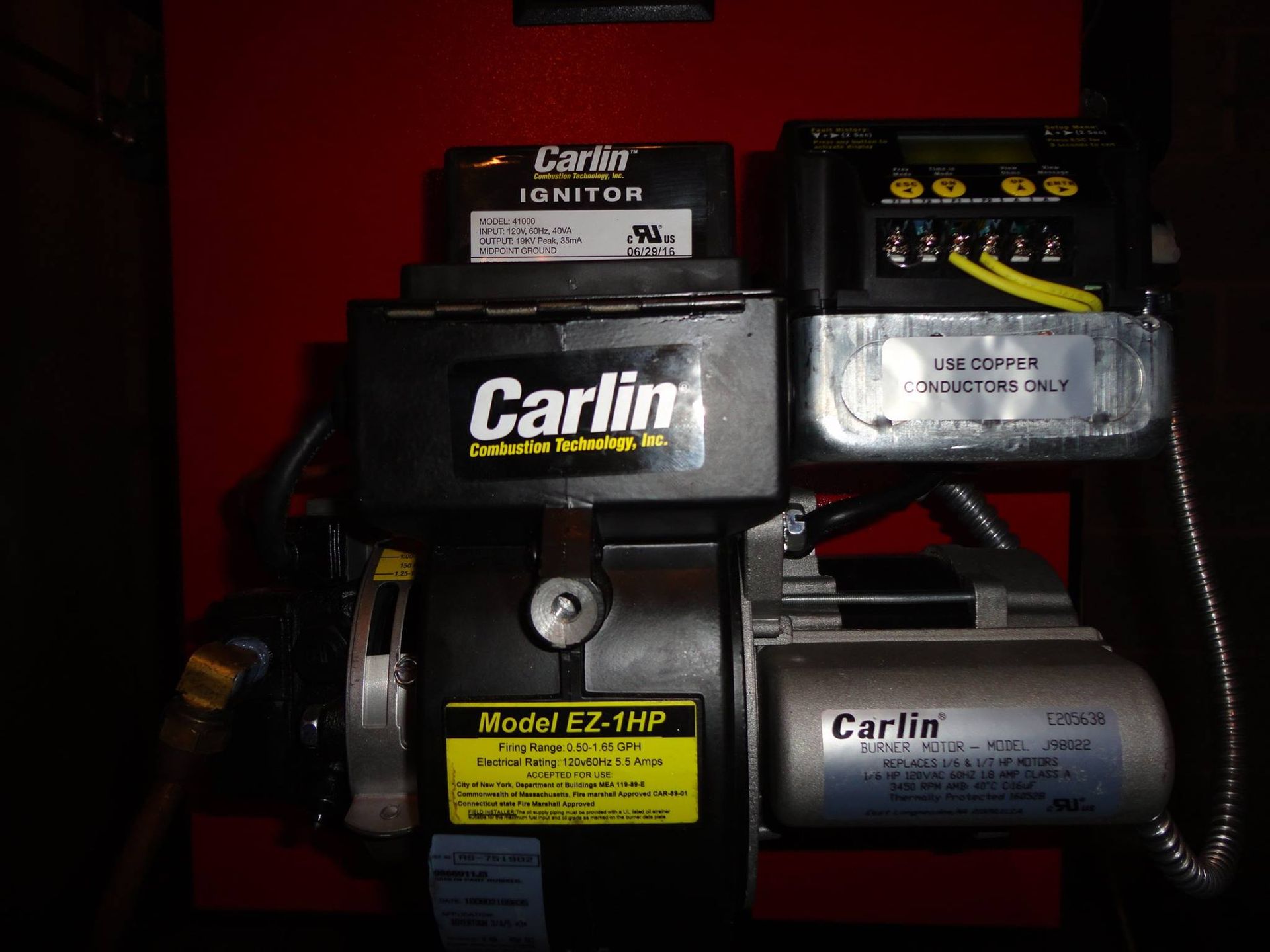 Oil burner with Carlin components mounted on a red panel.