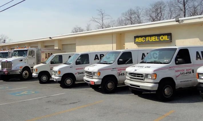 White vans and a truck parked outside a building labeled ABC Fuel Oil.