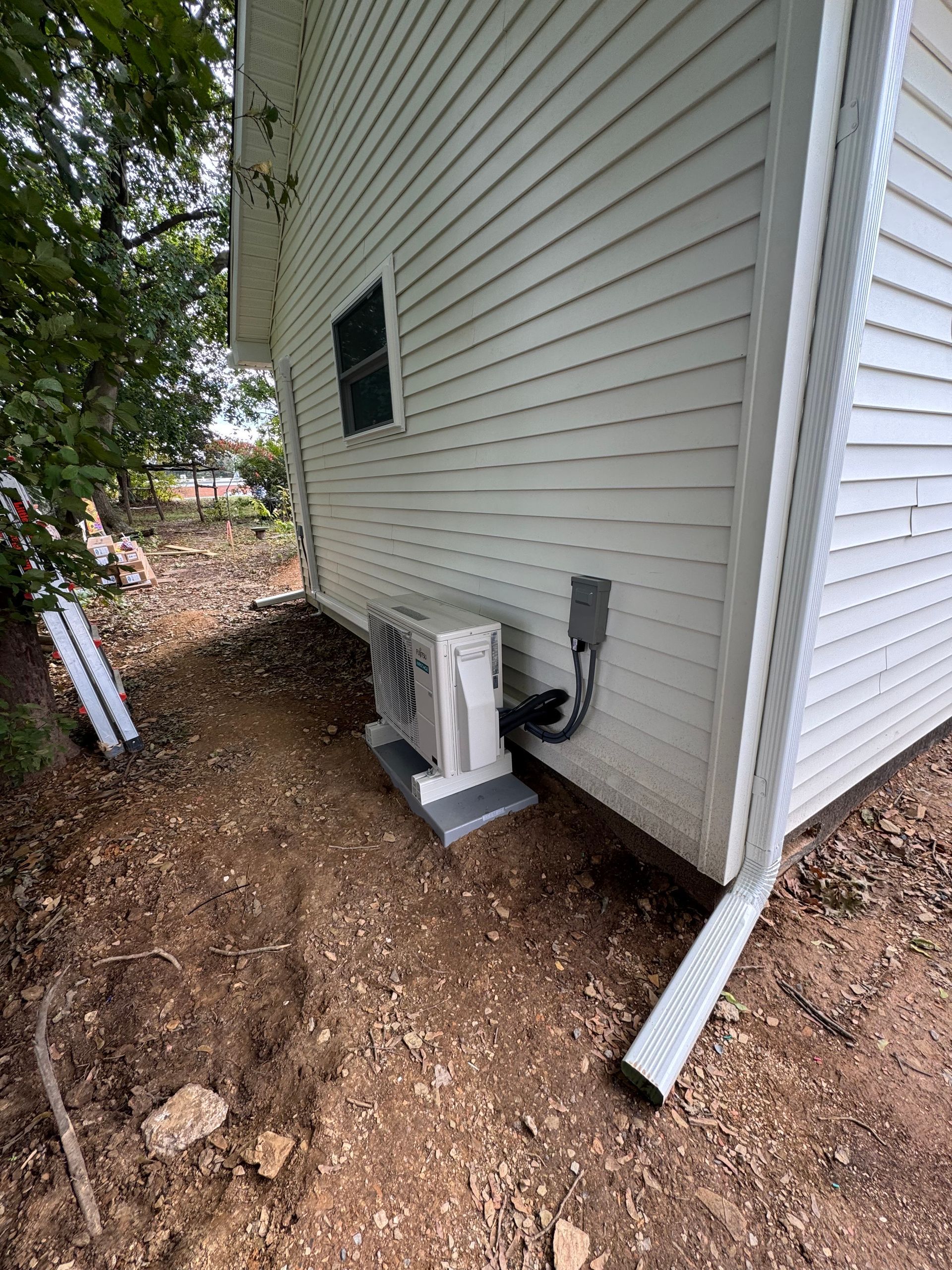 White house exterior with AC unit on concrete blocks near ground level.