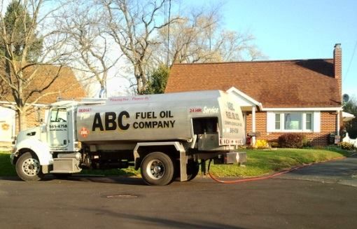 Fuel oil truck from ABC Fuel Oil Company parked at a house, orange hose connected.