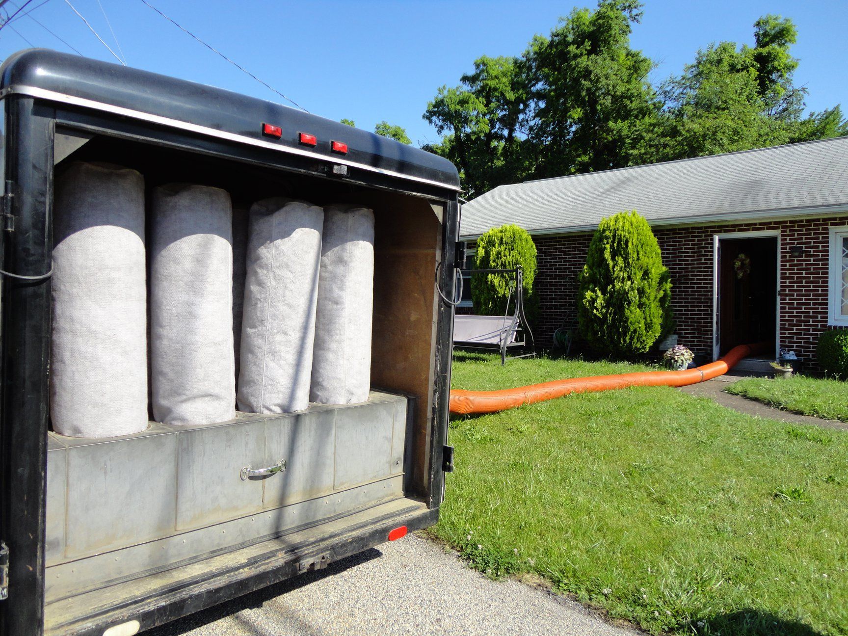 Insulation being blown into a house from a trailer in a front yard.