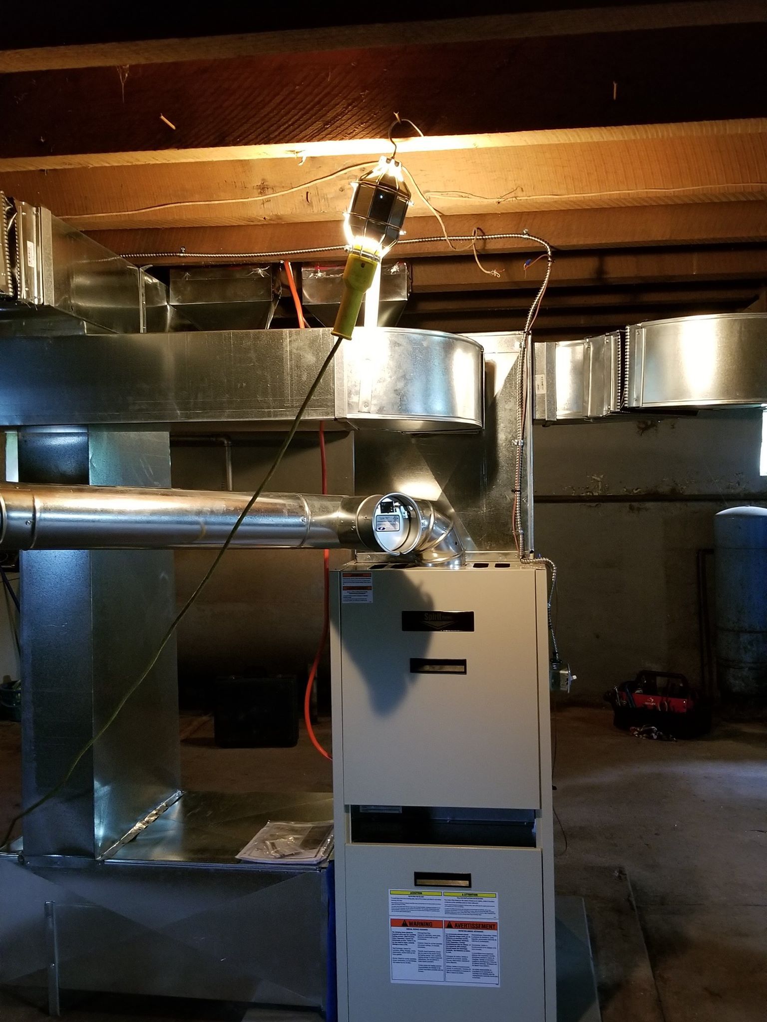 Sparks flying above a furnace, likely due to electrical issue, in a basement.